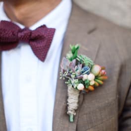 Succulent boutonniere pinned to a brown suit jacket