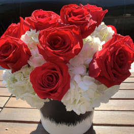 Red roses and white hydrangeas in a black-and-white vase