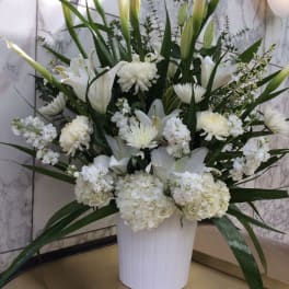 White floral arrangement in a white vase with tall calla lilies and chrysanthemums