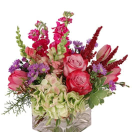 Low pink and purple mixed flower arrangement with hydrangea in a clear glass cube vase