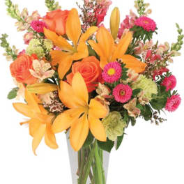Tall bouquet of orange lilies and roses with pink blooms in a clear glass vase