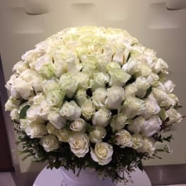 Large white rose arrangement in a white vase