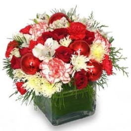 Compact red and white floral arrangement with ornaments in a clear glass cube vase