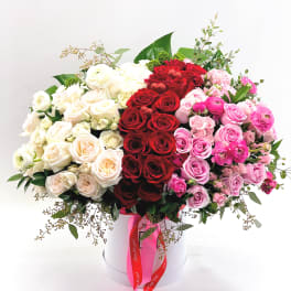 Large bouquet of red, white, and pink roses in a white hat box