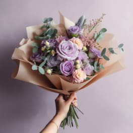 Bouquet of lavender and peach roses wrapped in tan paper