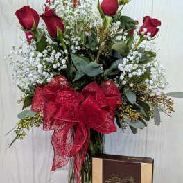 Red roses in a glass vase with a red bow and a box of truffles