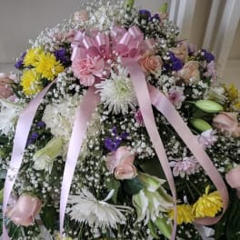 Large bouquet of pink roses, white lilies, and yellow chrysanthemums with a pink ribbon