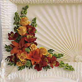 Casket spray with orange lilies, red flowers, and yellow roses