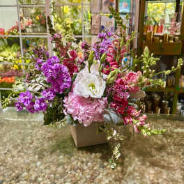 Pink, purple, and white flowers arranged in a square vase