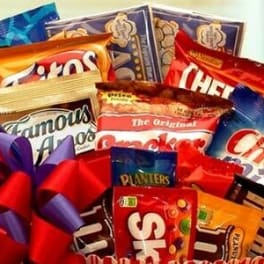 Gift basket filled with assorted snack and candy bags topped with a red and purple bow