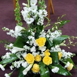 White and yellow floral arrangement with tall stems and broad leaves