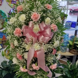 Large pink and white floral standing spray with a pink ribbon bow