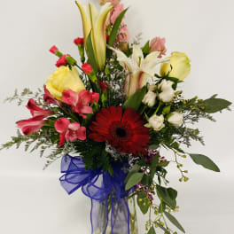 Mixed bouquet with lilies, gerbera daisy, and pink flowers in a glass vase