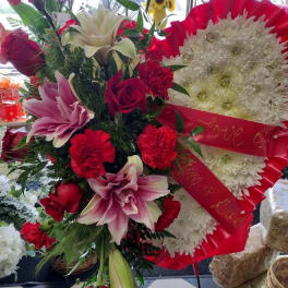 Red and white floral standing arrangement with lilies, roses, and chrysanthemums