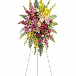 Standing spray of pink lilies, yellow flowers, and mixed blooms on a white easel