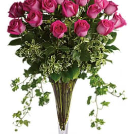 Tall arrangement of hot pink roses with trailing ivy in a clear glass vase