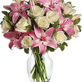 Bouquet of pink lilies and white roses arranged in a clear glass vase