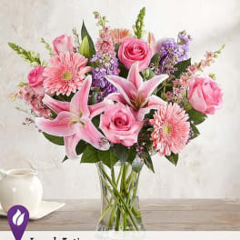 Pink roses, lilies, and gerbera daisies in a clear glass vase