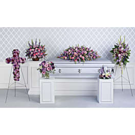 Lavender and pink funeral floral set with casket spray, cross, standing sprays and arrangements around a white casket