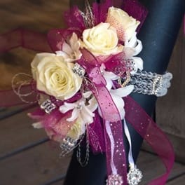 Corsage with cream roses, white flowers, and pink ribbon accents