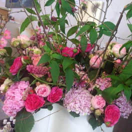 Large floral arrangement with pink roses and hydrangeas in a white container