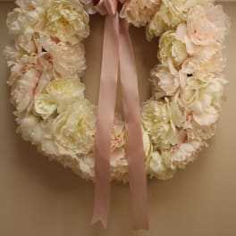 Cream floral wreath with a pink satin bow and long ribbon tails