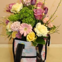 Mixed pastel flower arrangement in a patterned tote bag