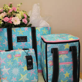 Pink and white flowers arranged in a blue patterned tote with matching bags