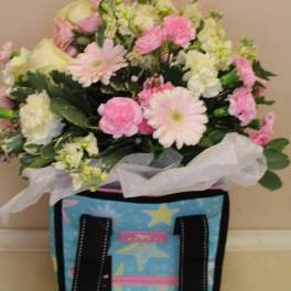 Pink and white mixed flower bouquet in a decorative tote bag