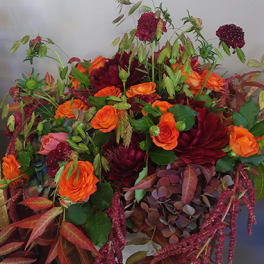 Large bouquet of orange and burgundy flowers with mixed foliage