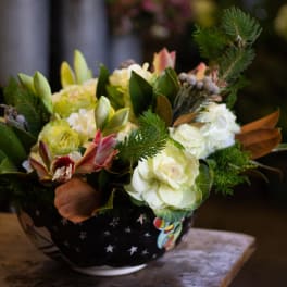 Mixed floral arrangement in a black bowl with white star pattern