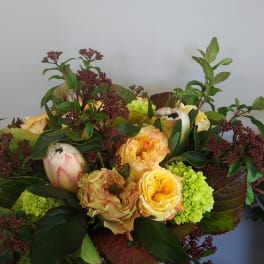 Bouquet of yellow roses and green blooms with burgundy foliage