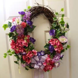 Floral wreath with pink and purple flowers and a plaid bow on a door