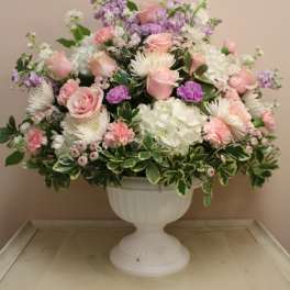 Pink and white floral arrangement in a white urn vase