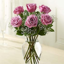 Pink roses arranged in a clear glass vase with baby's breath