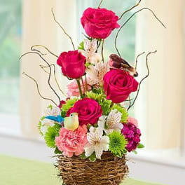 Pink roses and mixed flowers in a woven basket with bird decorations