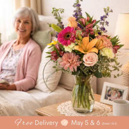 Mixed bouquet in a clear glass vase with pink, peach, and purple flowers