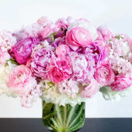 Compact arrangement of pink and white blooms in a clear glass vase