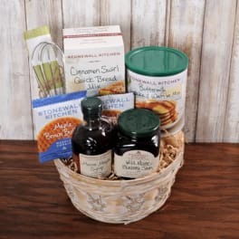 Breakfast-themed gift basket with baking mixes, maple syrup, jam, and a whisk