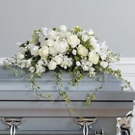 White floral casket spray with trailing vines on a silver casket
