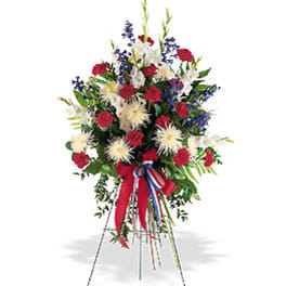 Tall red, white, and blue standing spray with carnations, mums, and ribbon on an easel