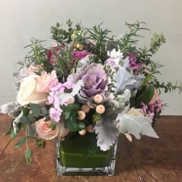 Mixed bouquet in a square glass vase with pink, white, and purple blooms