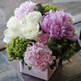 Pink and white flower arrangement in a pink box