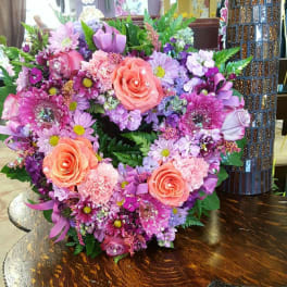 Heart-shaped bouquet of pink and purple flowers with peach roses