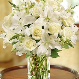 White lilies and roses arranged in a clear glass vase