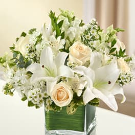 White lilies and cream roses in a square glass vase