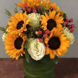 Sunflowers and white roses arranged in a green vase