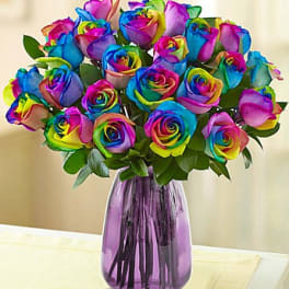 Bouquet of rainbow-colored roses in a purple glass vase