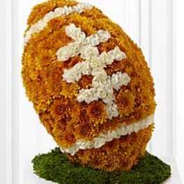 Orange and white floral arrangement shaped like a football on a green base