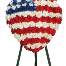 Heart-shaped red, white, and blue floral standing tribute on an easel